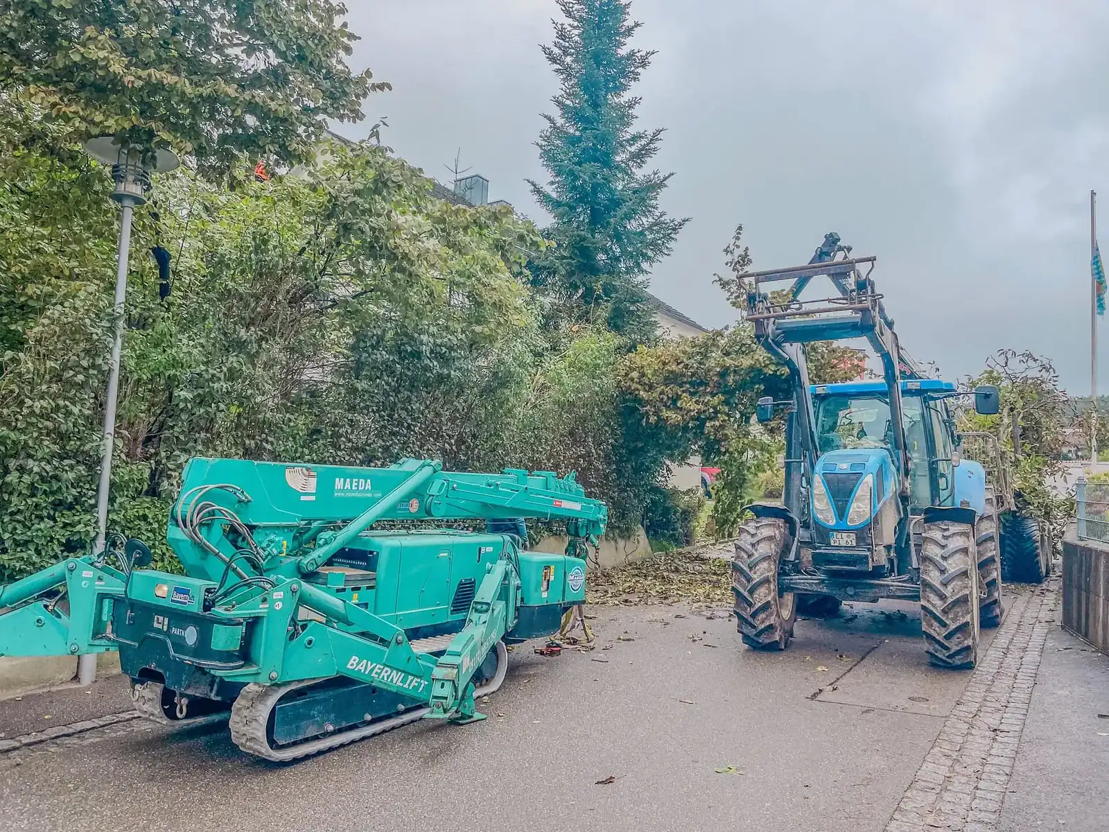 Raupenkran und Traktor der Evergreen Baumpflege in einer engen Wohnstraße
