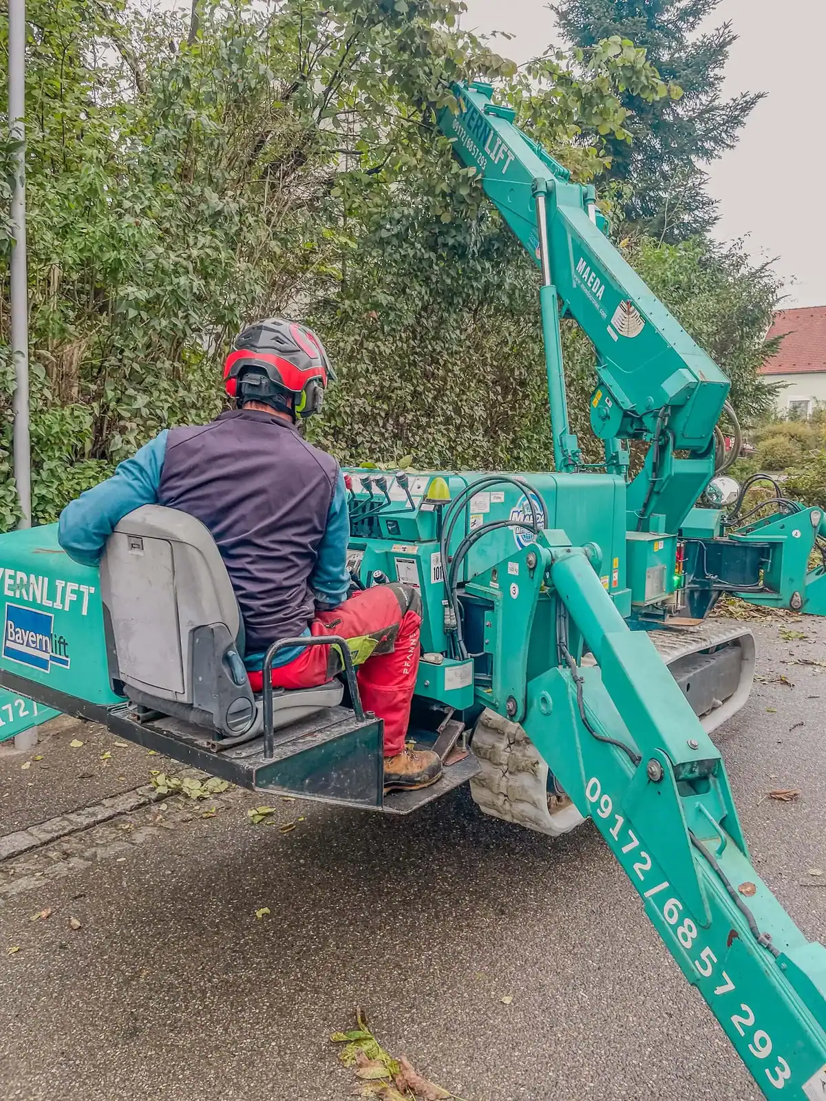 Mitarbeiter der Evergreen Baumpflege auf einer Raupen-Arbeitsbühne in einer Wohnstraße